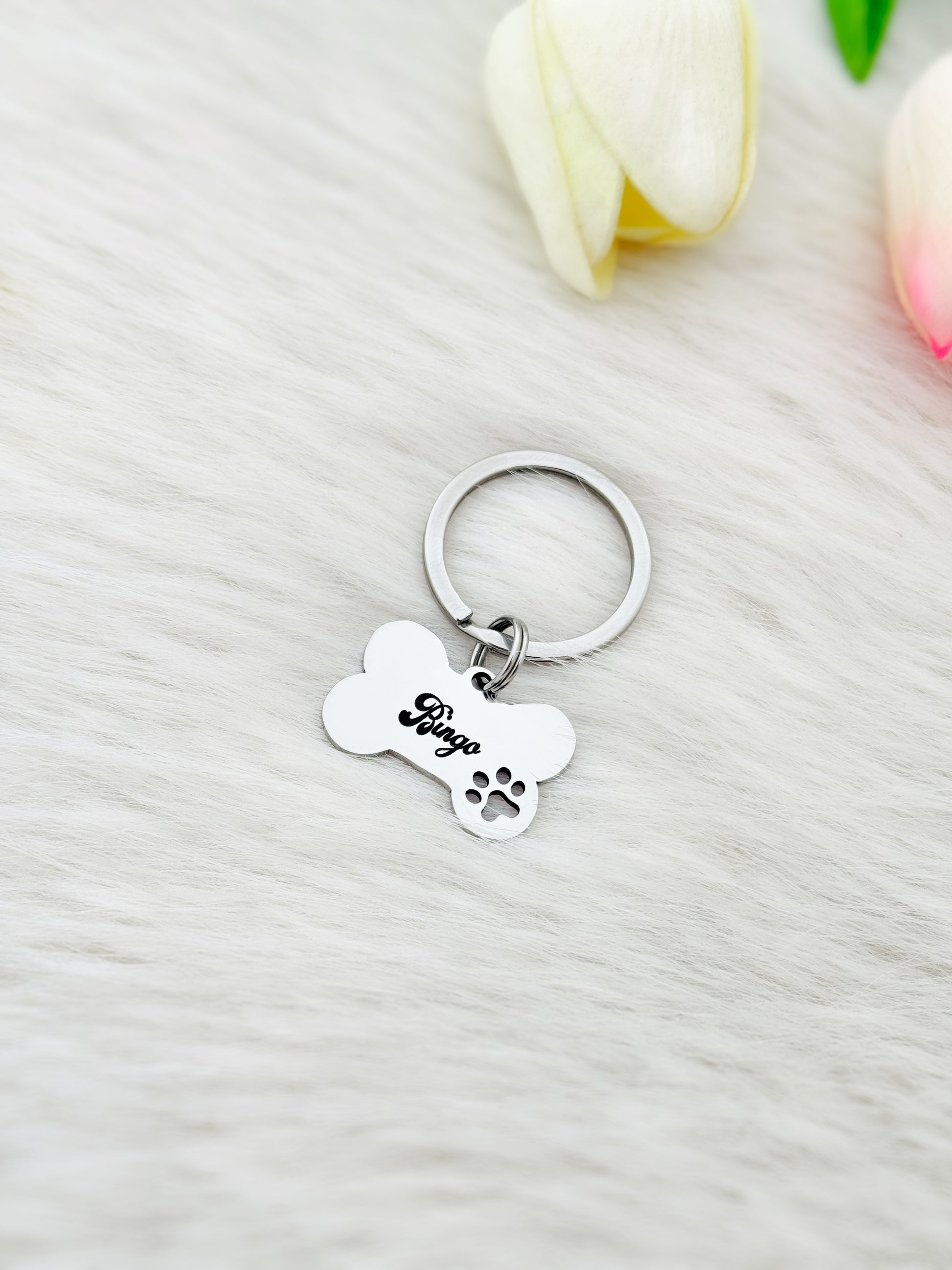Silver keychain with bone-shaped tag and paw print on a white surface